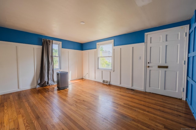 102 Vista Dr, East Haven, CT 06512 - unfurnished bedroom featuring a decorative wall, hardwood / wood-style floors, multiple windows, and a wainscoted wall
