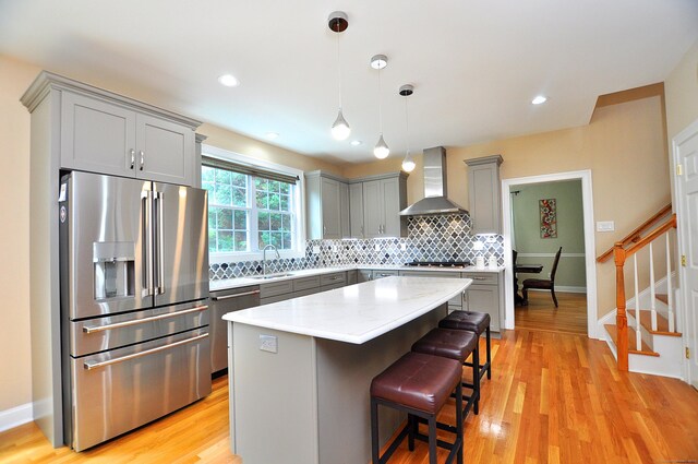 32 Arlington Dr, Avon, CT 06001 - kitchen with appliances with stainless steel finishes, wall chimney exhaust hood, gray cabinetry, decorative backsplash, and a kitchen bar