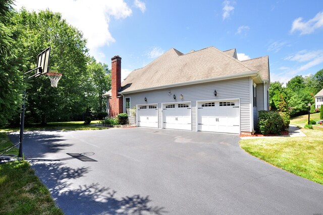 32 Arlington Dr, Avon, CT 06001 - view of side of property featuring asphalt driveway, a chimney, an attached garage, and a yard