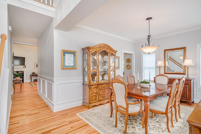 199 Meadow Brook Rd Unit 199, Oxford, CT 06478 - dining space with light wood-type flooring, ornamental molding, a wainscoted wall, a fireplace, and a decorative wall