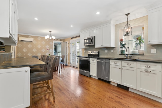 630 Fairview Ave, Bridgeport, CT 06606 - kitchen featuring appliances with stainless steel finishes, wallpapered walls, a chandelier, dark countertops, and a wall mounted AC
