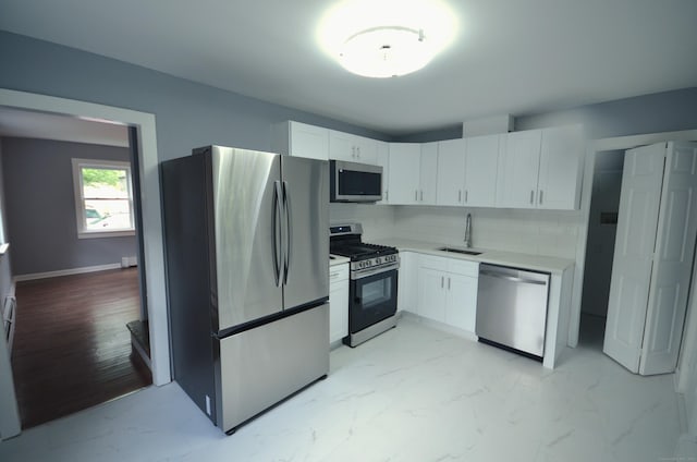 171 Wake St, Bridgeport, CT 06610 - kitchen featuring appliances with stainless steel finishes, backsplash, light countertops, white cabinetry, and light marble finish floors