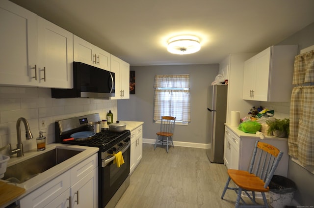 171 Wake St, Bridgeport, CT 06610 - kitchen featuring stainless steel appliances, light countertops, backsplash, white cabinetry, and light wood-style flooring
