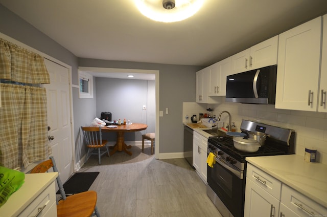 171 Wake St, Bridgeport, CT 06610 - kitchen with stainless steel appliances, light countertops, decorative backsplash, white cabinets, and light wood-style flooring
