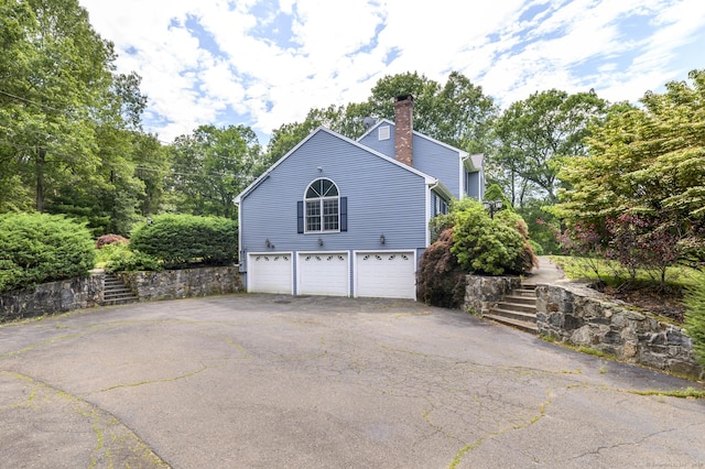 491 Hammertown Rd, Monroe, CT 06468 - view of side of home with asphalt driveway, a garage, a chimney, and stairway