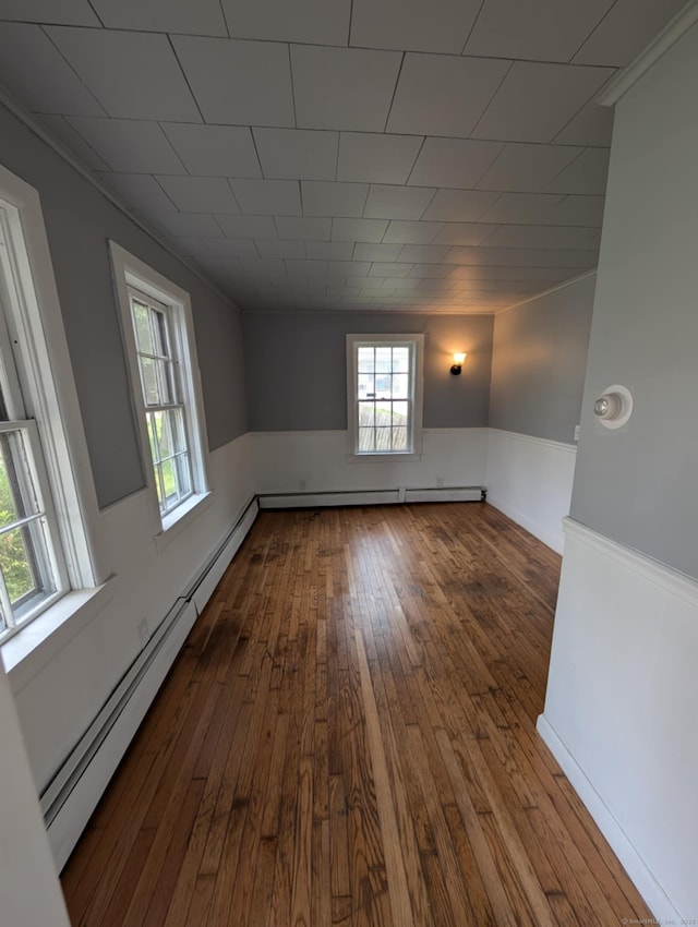 18 Highland St, Plainfield, CT 06354 - empty room featuring baseboard heating, wood-type flooring, plenty of natural light, a wainscoted wall, and ornamental molding