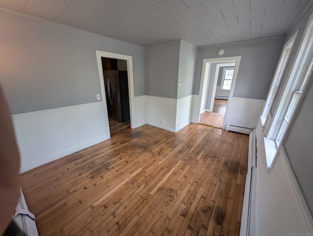 18 Highland St, Plainfield, CT 06354 - unfurnished room featuring a baseboard heating unit, wood-type flooring, ornamental molding, wainscoting, and a smoke detector