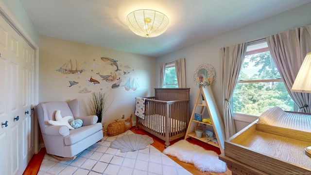 803 Grassy Hill Rd, Orange, CT 06477 - bedroom featuring multiple windows, a crib, a closet, and light wood-style floors