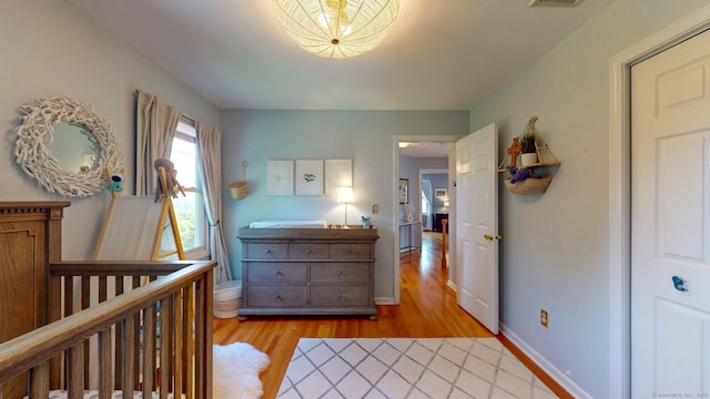 803 Grassy Hill Rd, Orange, CT 06477 - bedroom with light wood-style flooring, a nursery area, and a chandelier