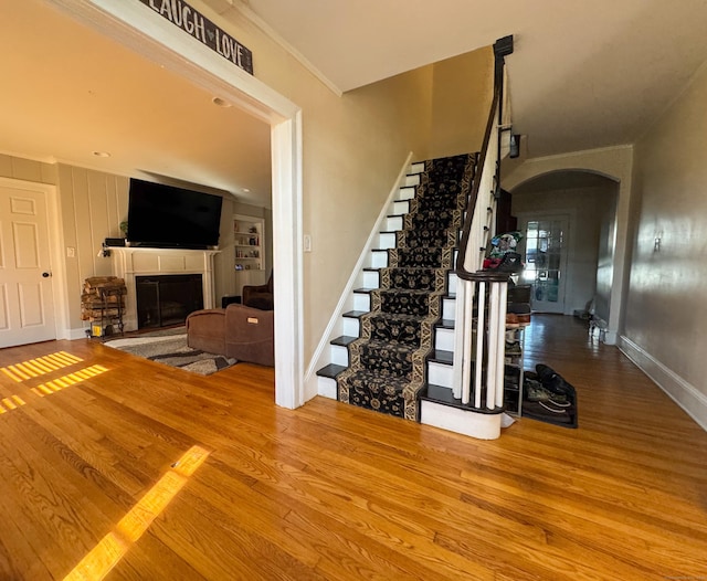 1589 Main St, East Hartford, CT 06108 - stairway featuring arched walkways, wood finished floors, a glass covered fireplace, and crown molding