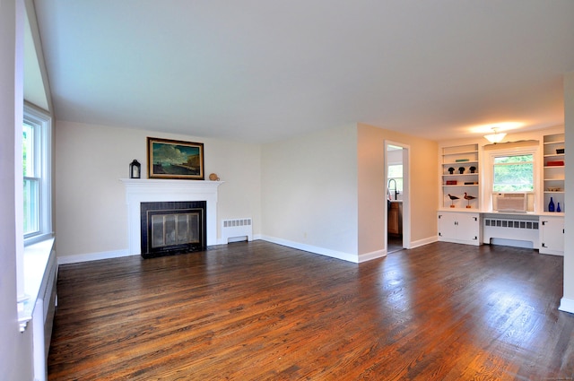 47 Westwood Dr, Simsbury, CT 06070 - unfurnished living room featuring radiator heating unit, a fireplace with flush hearth, dark wood-style floors, and built in features