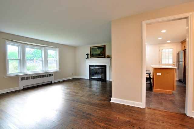 47 Westwood Dr, Simsbury, CT 06070 - unfurnished living room featuring radiator heating unit, dark wood-type flooring, a glass covered fireplace, and recessed lighting