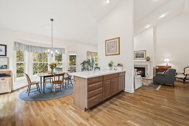 39 Emily Way Unit 39, West Hartford, CT 06107 - kitchen featuring light wood-style floors, a warm lit fireplace, a chandelier, high vaulted ceiling, and light countertops