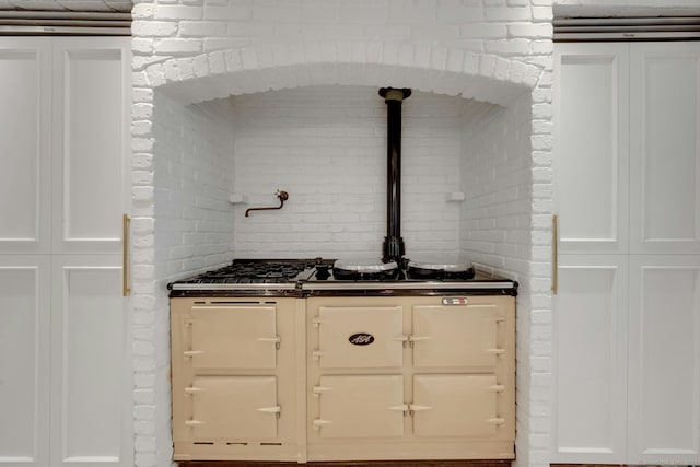 2024 Stratfield Rd, Fairfield, CT 06825 - kitchen with dark countertops, white cabinetry, and brick wall