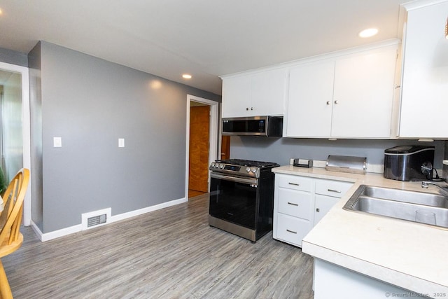 136 Chatham St, Hartford, CT 06112 - kitchen with appliances with stainless steel finishes, light countertops, recessed lighting, white cabinetry, and light wood-style floors