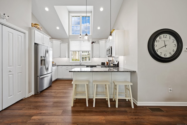 31 Old Oak Ct, Southington, CT 06489 - kitchen featuring stainless steel appliances, a peninsula, tasteful backsplash, dark wood-style flooring, and dark stone counters