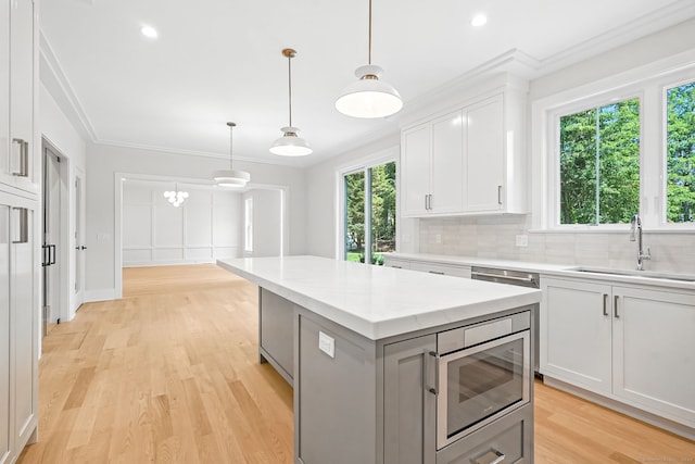 28 Pin Oak Ct, Westport, CT 06880 - kitchen featuring stainless steel microwave, backsplash, a kitchen island, white cabinetry, and light wood finished floors