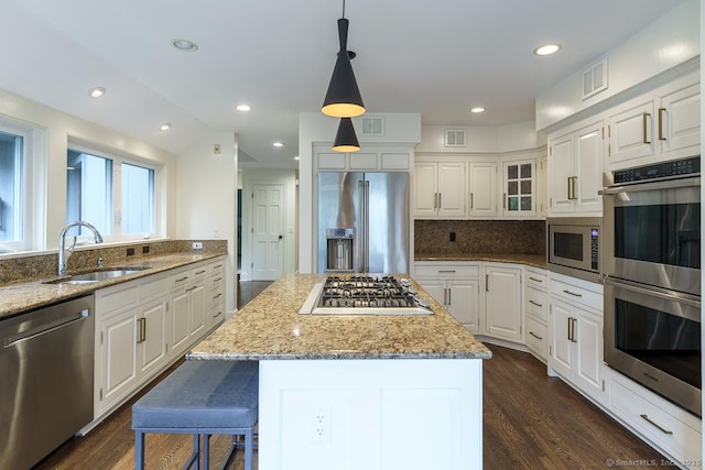19 Money Point Rd, Stonington, CT 06355 - kitchen with stainless steel appliances, light stone counters, white cabinetry, dark wood-type flooring, and a kitchen island