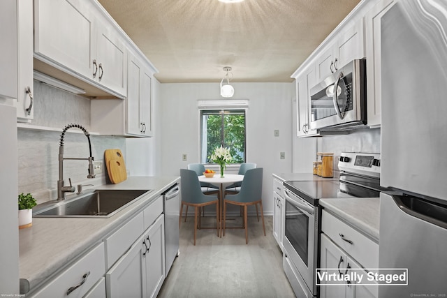 241 Heritage Vlg Unit C, Southbury, CT 06488 - kitchen with appliances with stainless steel finishes, tasteful backsplash, white cabinets, light wood-type flooring, and light countertops