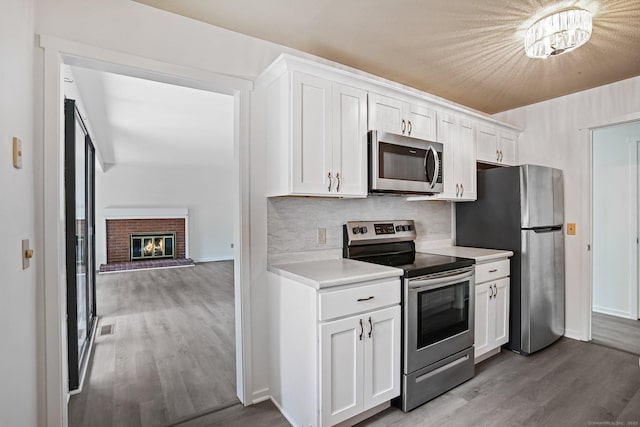 241 Heritage Vlg Unit C, Southbury, CT 06488 - kitchen featuring stainless steel appliances, wood finished floors, light countertops, white cabinets, and decorative backsplash