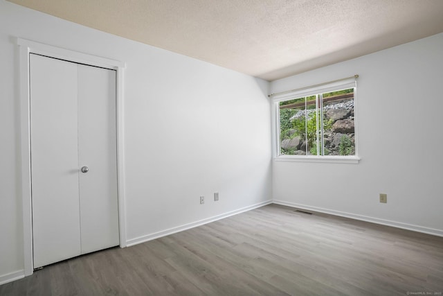 241 Heritage Vlg Unit C, Southbury, CT 06488 - unfurnished bedroom featuring wood finished floors, a textured ceiling, and a closet