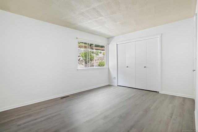 241 Heritage Vlg Unit C, Southbury, CT 06488 - unfurnished bedroom featuring wood finished floors, a closet, and a textured ceiling
