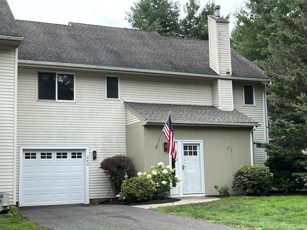 260 Alewife Ln Unit 260, Suffield, CT 06078 - back of house featuring a chimney, a garage, driveway, and a shingled roof