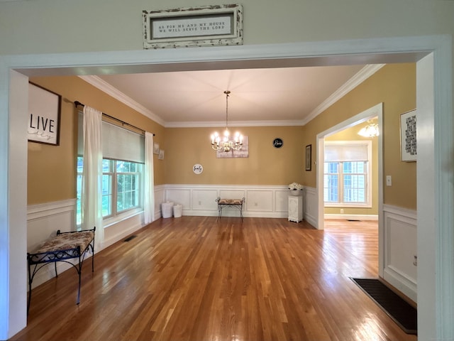 41 Calloway Dr, Milford, CT 06461 - unfurnished dining area with healthy amount of natural light, a chandelier, wood finished floors, ornamental molding, and a decorative wall