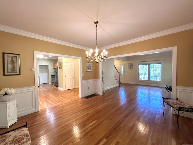 41 Calloway Dr, Milford, CT 06461 - unfurnished dining area featuring ornamental molding, stairway, light wood-type flooring, a chandelier, and wainscoting