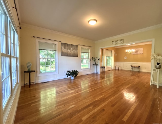 41 Calloway Dr, Milford, CT 06461 - unfurnished living room featuring a chandelier, wood finished floors, ornamental molding, and a wainscoted wall