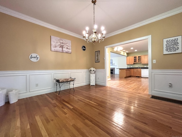 41 Calloway Dr, Milford, CT 06461 - dining area with a chandelier, ornamental molding, wood finished floors, a decorative wall, and a wainscoted wall