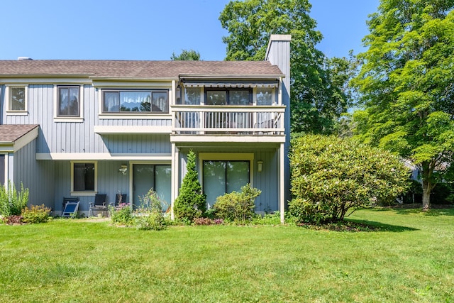 291 Heritage Vlg Unit C, Southbury, CT 06488 - back of property featuring a balcony, a chimney, a lawn, and roof with shingles