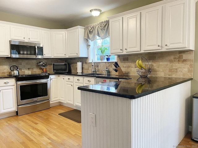 1040 Purchase Brook Rd, Southbury, CT 06488 - kitchen with appliances with stainless steel finishes, dark countertops, white cabinetry, and backsplash
