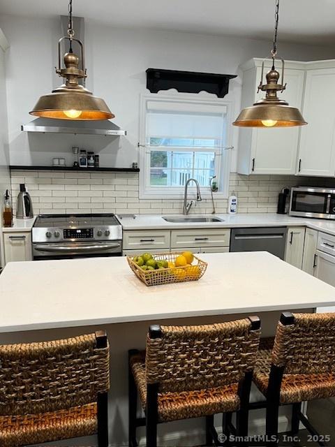 85 W Thames St, Norwich, CT 06360 - kitchen featuring appliances with stainless steel finishes, a kitchen breakfast bar, decorative backsplash, and pendant lighting