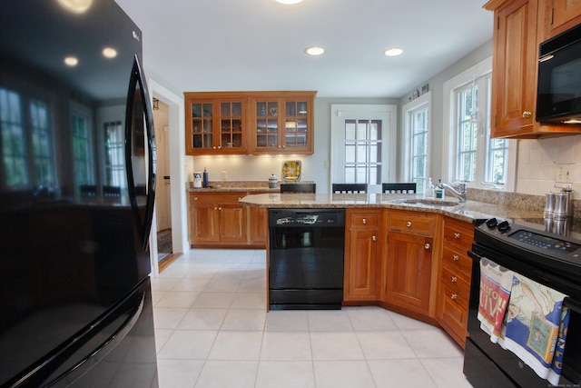23 Mountain View Dr, West Hartford, CT 06117 - kitchen with black appliances, brown cabinets, a peninsula, light stone countertops, and glass insert cabinets