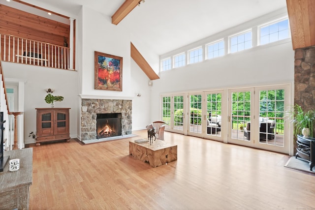 168 Sunset Hill Rd, Redding, CT 06896 - living room with a towering ceiling, a stone fireplace, wood finished floors, a wood stove, and beamed ceiling