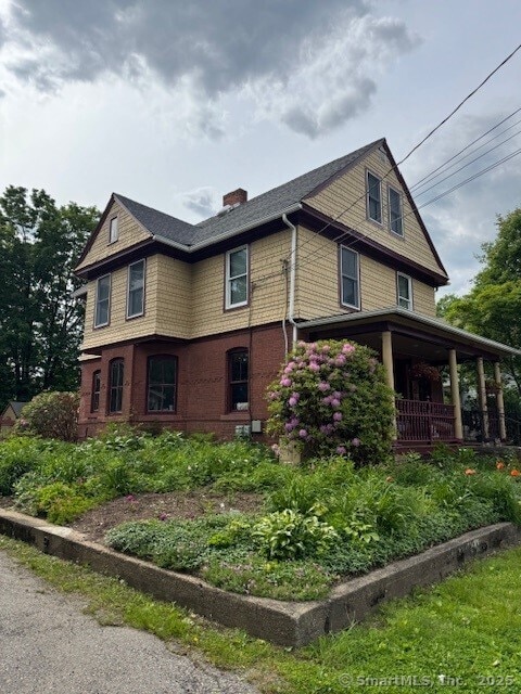 240 Walnut St, Windham, CT 06226 - view of side of home with a chimney and covered porch