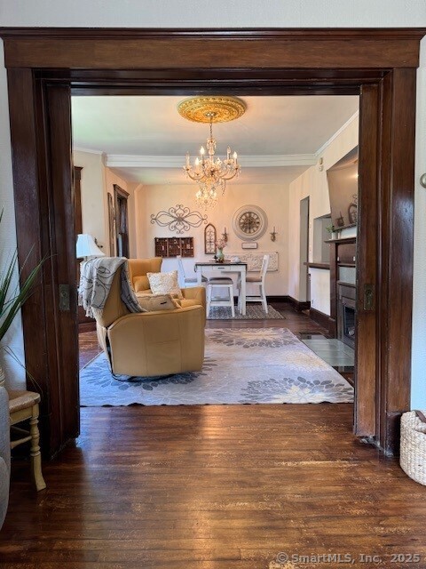 240 Walnut St, Windham, CT 06226 - living room featuring a chandelier, wood finished floors, crown molding, and a fireplace with flush hearth