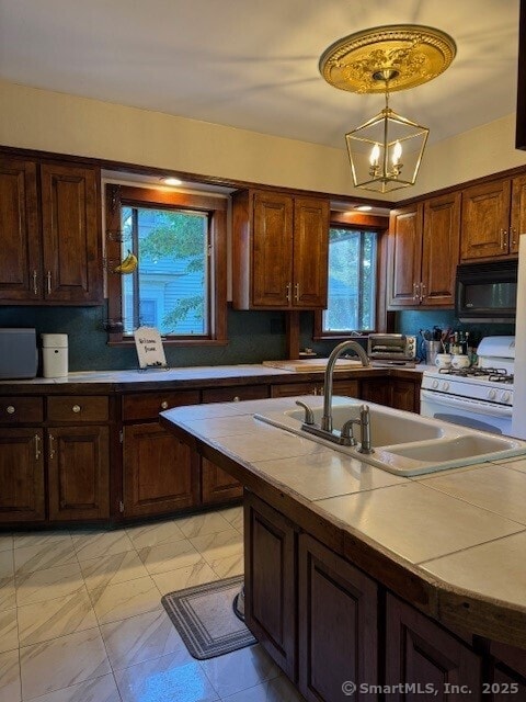 240 Walnut St, Windham, CT 06226 - kitchen with black microwave, white range with gas cooktop, light countertops, a chandelier, and decorative light fixtures