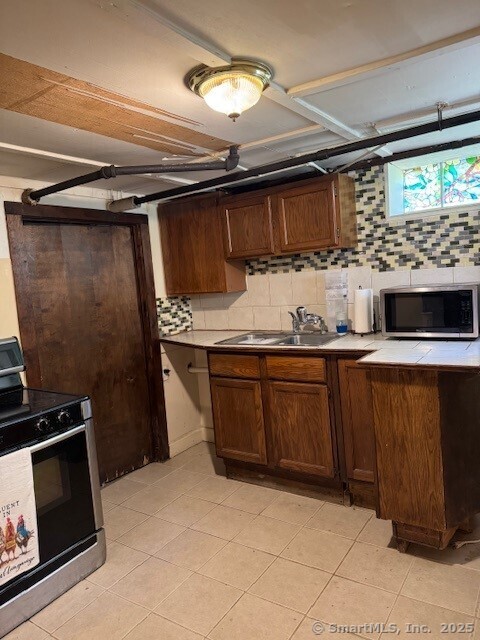 240 Walnut St, Windham, CT 06226 - kitchen featuring appliances with stainless steel finishes, decorative backsplash, light tile patterned floors, and light countertops