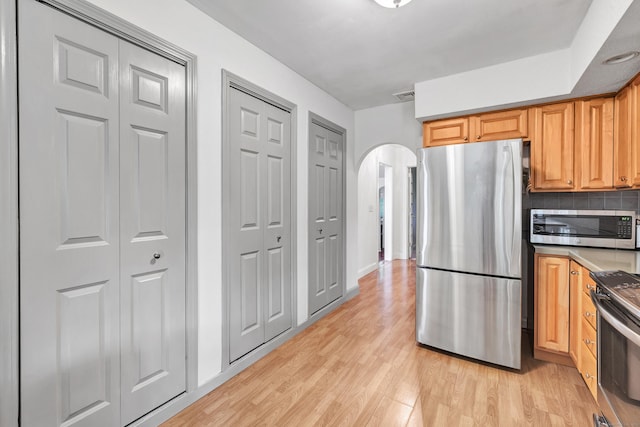 3 Yale Ave, Shelton, CT 06484 - kitchen featuring appliances with stainless steel finishes, arched walkways, light wood-style floors, and decorative backsplash