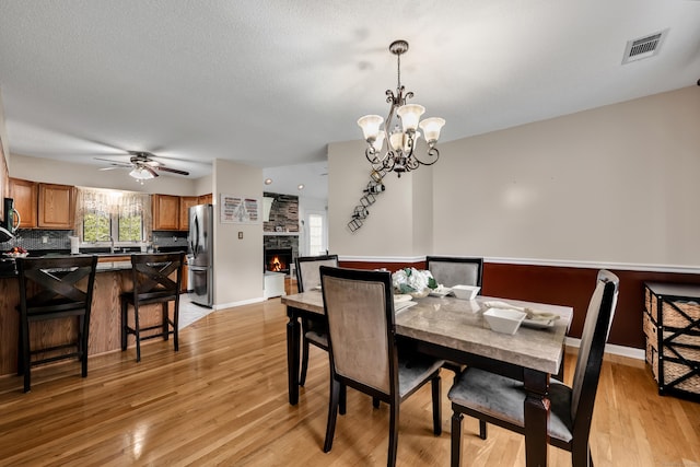 114 Tiffany Ln, Bristol, CT 06010 - dining room featuring light wood-type flooring, a ceiling fan, a fireplace, and a chandelier