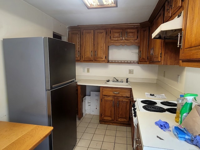 173 Fairview Ave, Bridgeport, CT 06606 - kitchen with freestanding refrigerator, under cabinet range hood, light countertops, light tile patterned flooring, and brown cabinetry