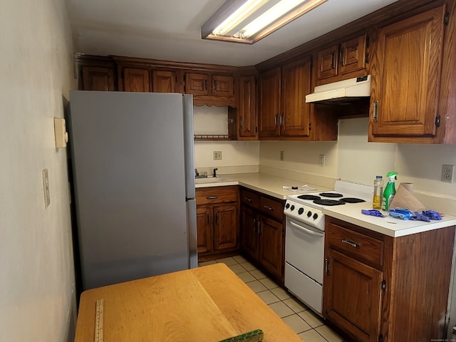173 Fairview Ave, Bridgeport, CT 06606 - kitchen featuring freestanding refrigerator, white electric range, under cabinet range hood, light tile patterned floors, and light countertops