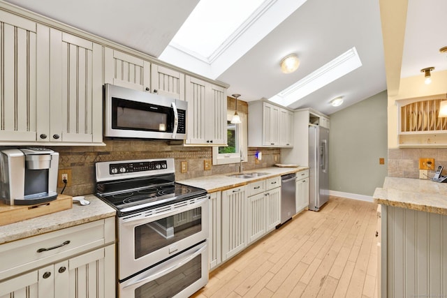 11 Harrington Rd, East Windsor, CT 06016 - kitchen with stainless steel appliances, decorative backsplash, light stone countertops, a skylight, and light wood finished floors