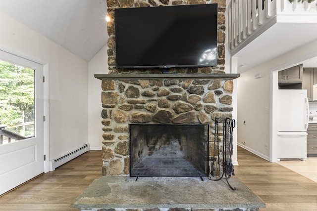 30 W Woods Rd, Burlington, CT 06013 - detailed view of freestanding refrigerator, a baseboard heating unit, wood finished floors, and a fireplace