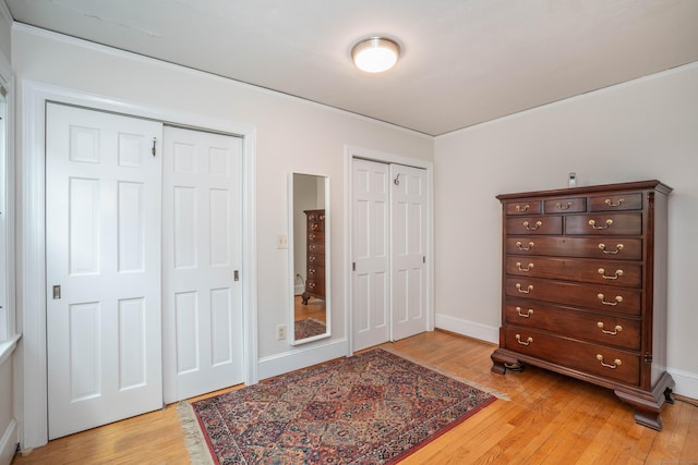 169 Brace Rd, West Hartford, CT 06107 - bedroom with two closets, light wood-type flooring, and ornamental molding