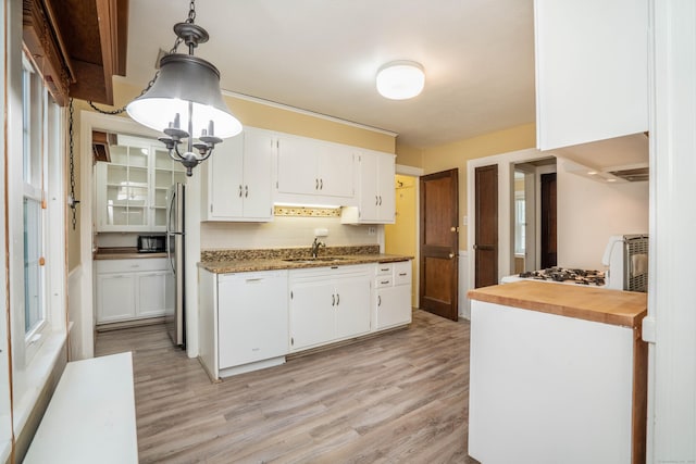 169 Brace Rd, West Hartford, CT 06107 - kitchen with light wood finished floors, white cabinets, freestanding refrigerator, backsplash, and decorative light fixtures