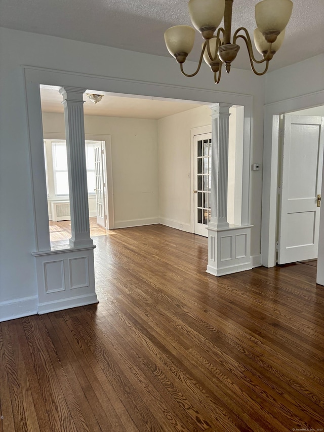 138 Mill Hill Ave, Bridgeport, CT 06610 - unfurnished room with decorative columns, dark wood-style flooring, and a chandelier