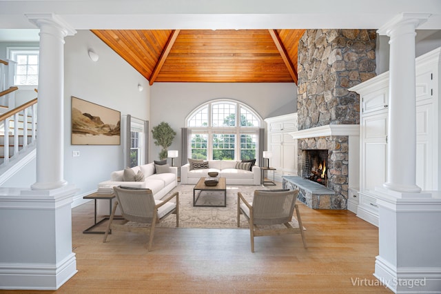 125 Nod Hill Rd, Wilton, CT 06897 - living room with a wooden ceiling with exposed beams, light wood-style floors, stairway, a stone fireplace, and decorative columns